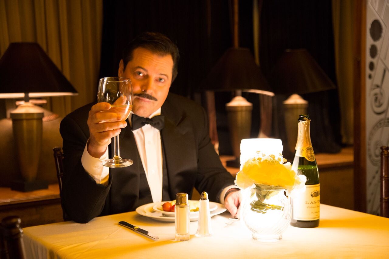 A man in a tuxedo holding a glass of wine.